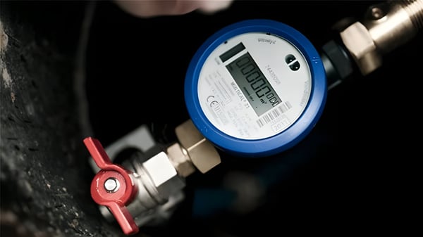Close-up of a blue Diehl Metering digital smart water meter installed on a pipe with a red valve handle.
