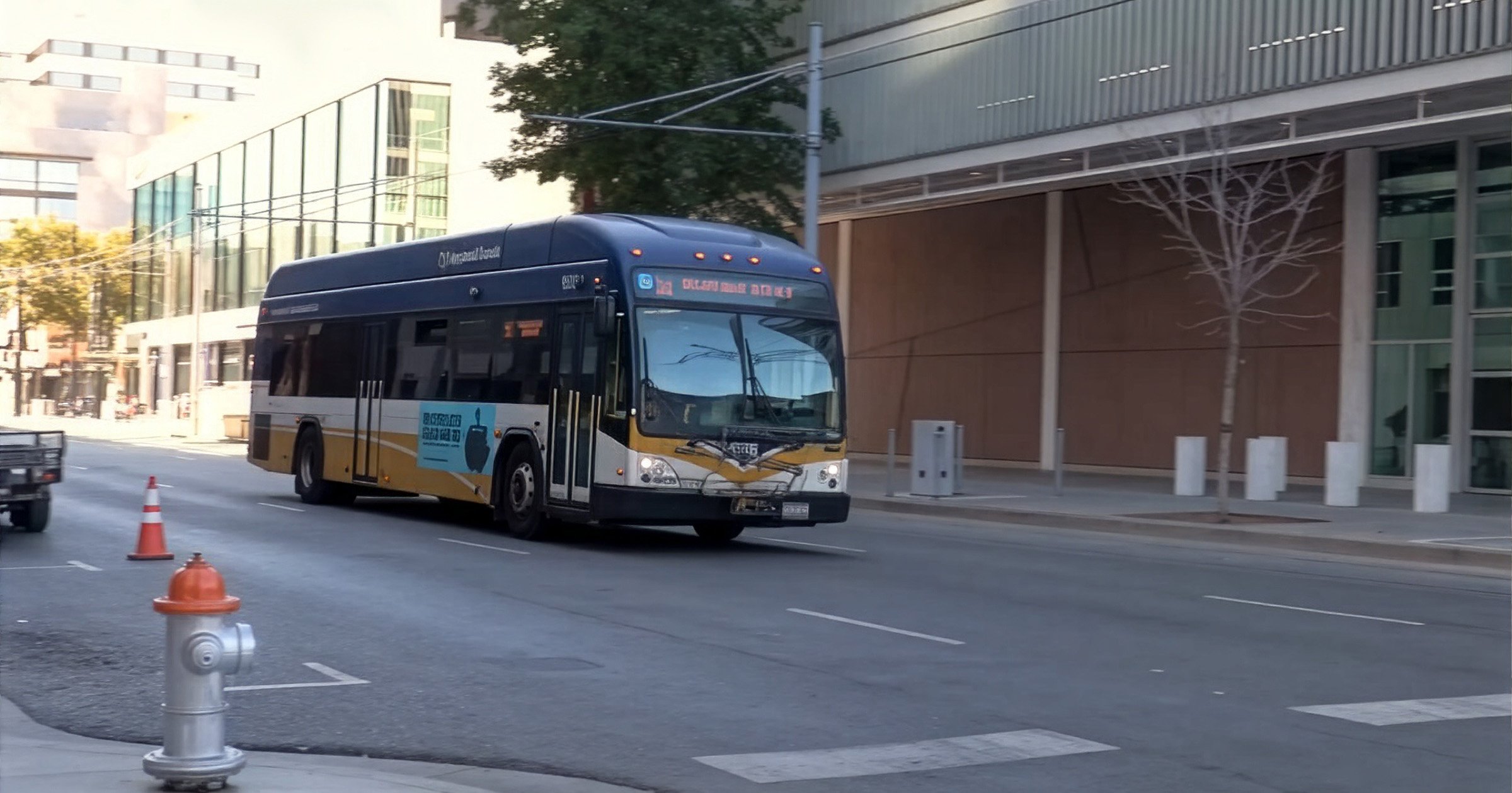 Sacramento Regional Transit bus driving on a city street past a modern building and a silver fire hydrant.