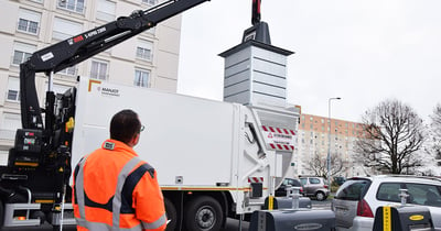 A man standing beside a a smart waste garbage collectection truck.