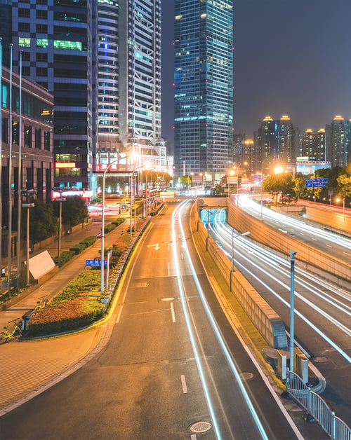 A bustling smart city street at night, illuminated by LED lights that are connected to a lighting control cabinet