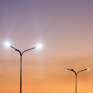 Vibrant sunset backdrop with two street lights shining brightly in the evening.