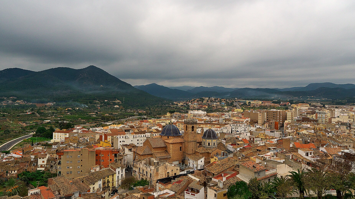Elevated view of the historic town of Onda, Spain, featuring tiled roofs and church domes under a cloudy sky