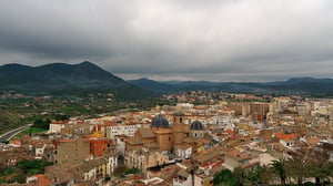Elevated view of the historic town of Onda, Spain, featuring tiled roofs and church domes under a cloudy sky