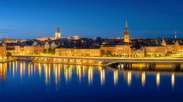 Stockholm's Gamla Stan skyline at dusk with illuminated buildings and street lights reflecting on the water
