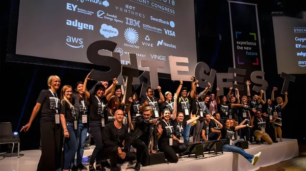 A group on stage holding large STHLM TECH FEST letters in front of a screen displaying AWS, IBM, and Salesforce logos.