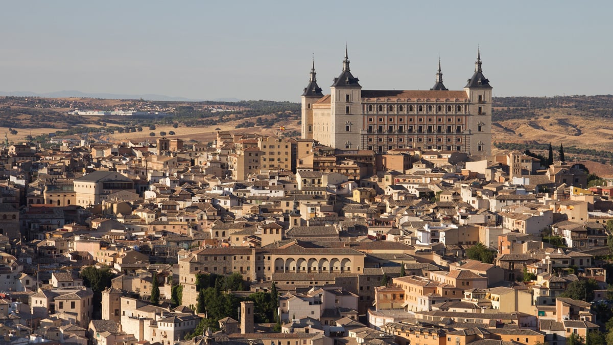 Panoramic view of the historic quarter of Toledo, Spain, featuring the Alcázar stone fortification and dense urban housing.