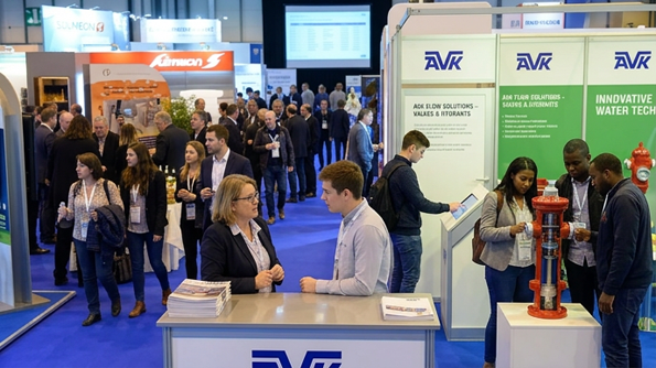 Attendees gather at an AVK exhibition booth displaying water technology and fire hydrants at a busy trade show.