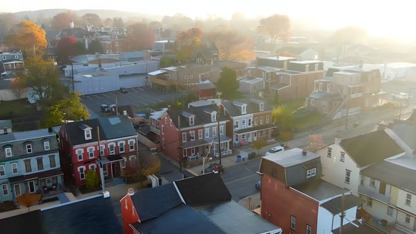 Aerial drone view of a residential neighborhood with brick row houses and autumn trees in morning mist.