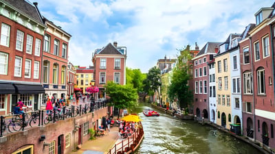 Traditional brick buildings and a tour boat along the Oudegracht canal in Utrecht, Netherlands.