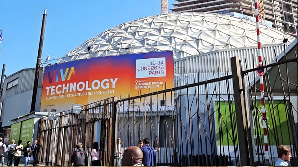 Large Viva Technology 2025 banner on a geodesic dome building with attendees walking past a metal fence in Paris.