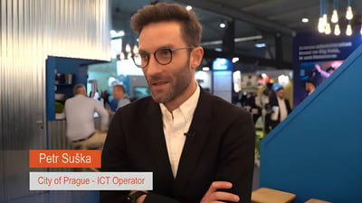 Petr Suška, City of Prague ICT Operator, speaking at a smart city event with an orange and white name graphic.