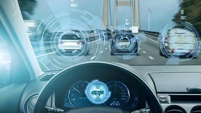 Driver's view of a highway with digital V2X overlays highlighting surrounding vehicles and a suspension bridge ahead.