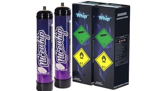 Two purple Nicewhip nitrous oxide cream charger canisters standing next to two black Whip branded cardboard boxes