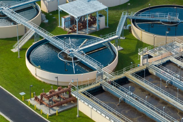 Aerial view of circular clarifier tanks and rectangular filtration basins at a water treatment plant.
