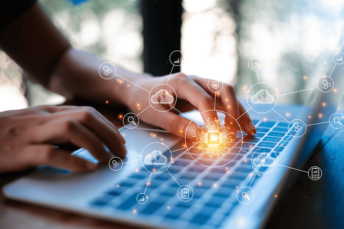 Illustration of a shield protecting data from cyberattacks on an IoT platform in overlay over a laptop being used by an individual.