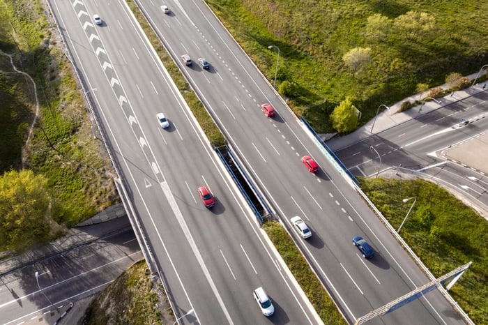 Aerial view of cars driving on a smart motorway, showcasing the bustling traffic and the vastness of the road network.