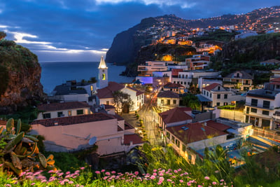 Illuminated coastal town of Câmara de Lobos in Madeira with street lights glowing at dusk
