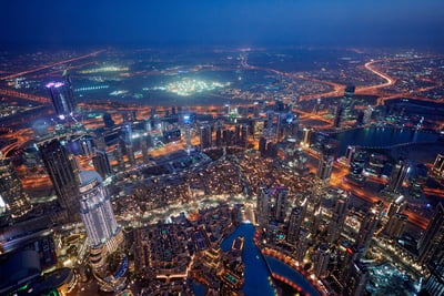 Aerial high-angle view of the illuminated Dubai skyline and highway network at night