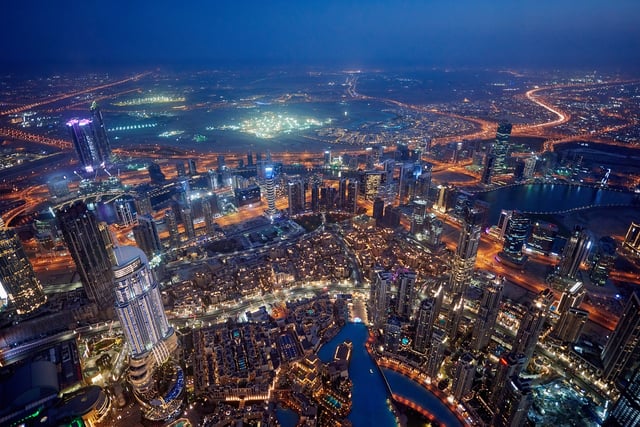 Aerial high-angle view of the illuminated Dubai skyline and highway network at night