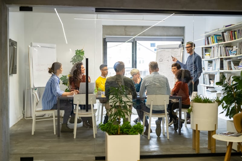 A group of executives discussing project business case and strategy around a flipboard