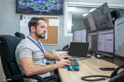 A man sitting at a desk with a computer in a smart city control center