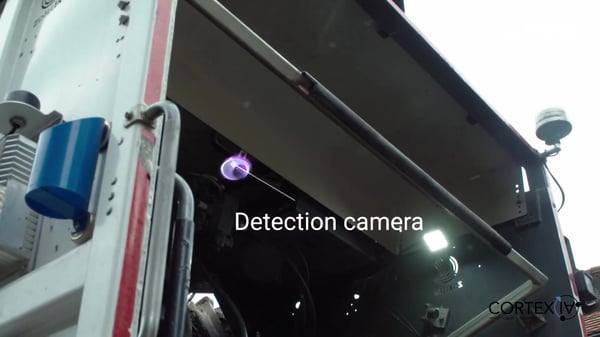 Low-angle view of a detection camera and sensors mounted on the rear of a waste collection vehicle.