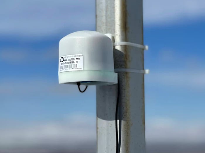 purple air sensor measuring aur quality mounted on a pole