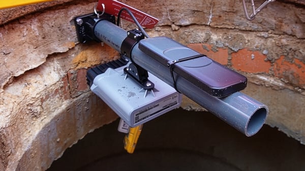 Flood monitoring IoT sensors and equipment mounted on a PVC pipe inside a brick manhole.