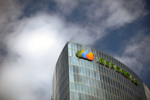 Low-angle view of the Iberdrola logo on a curved glass office building under a cloudy sky.
