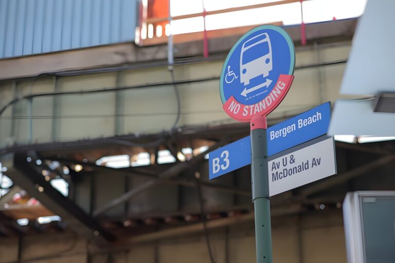 A New York City B3 bus stop sign for Bergen Beach at Avenue U and McDonald Avenue under an elevated train track.