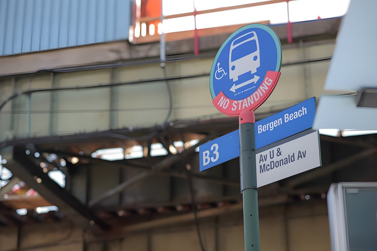 A New York City B3 bus stop sign for Bergen Beach at Avenue U and McDonald Avenue under an elevated train track.