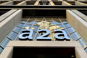 Low-angle view of the A2A company logo mounted on a glass and stone building facade.