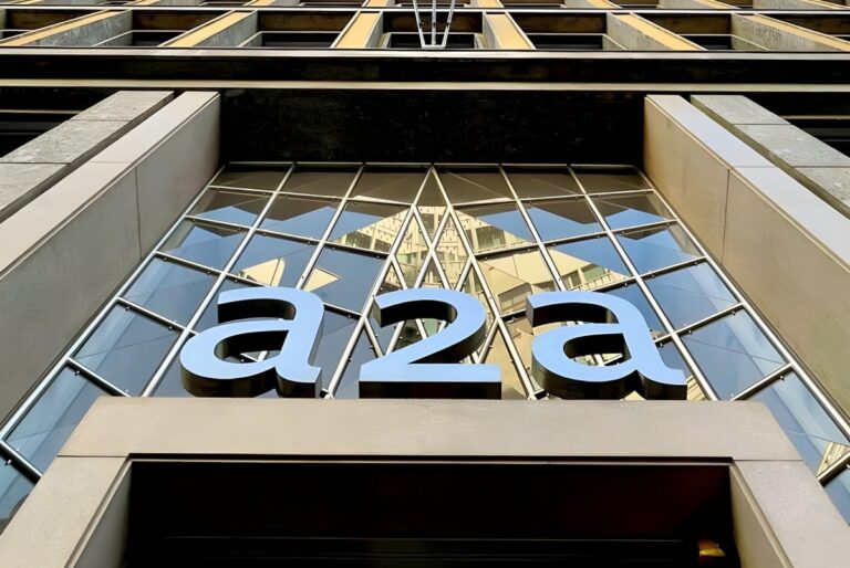 Low-angle view of the A2A company logo mounted on a glass and stone building facade.