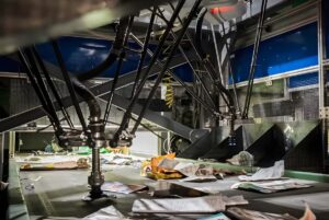 AMP Robotics high-speed delta robots sorting paper and plastic waste on a conveyor belt in a recycling facility.