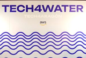 A white wall display featuring Tech4Water and Tech4Aragón text above an AWS logo and blue wave patterns.