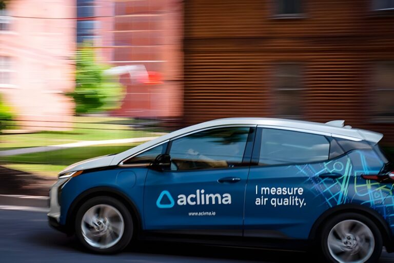 An Aclima mobile air quality monitoring vehicle driving past a residential building.