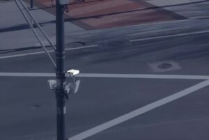 An Aeva LiDAR sensor and traffic cameras mounted on a utility pole overlooking a city intersection.