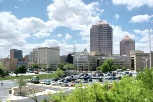 Skyline of downtown Albuquerque featuring the Albuquerque Plaza and Hyatt Regency towers behind a surface parking lot.