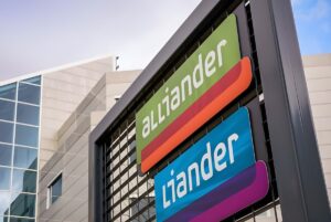 Alliander and Liander company logos on a metal outdoor sign in front of a modern office building.