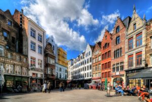 Pedestrians and outdoor cafe seating in a public square surrounded by historic gabled buildings in Antwerp, Belgium.