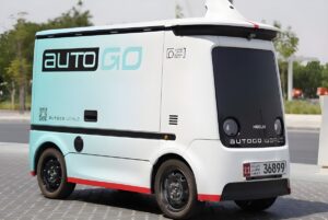 An Autogo autonomous robosweeper vehicle parked on a paved sidewalk in Abu Dhabi.
