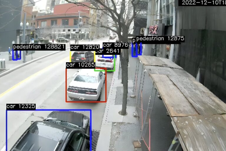 Automotus AI camera view of a city street with digital bounding boxes identifying parked cars and pedestrians.