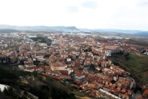 Aerial view of the city of Soria, Spain, featuring red-roofed buildings and surrounding hills.