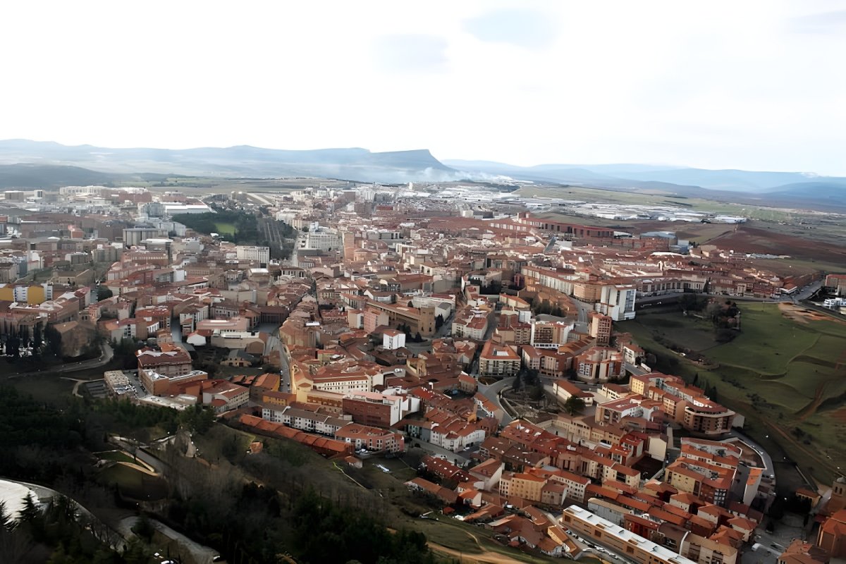 Aerial view of the city of Soria, Spain, featuring red-roofed buildings and surrounding hills.