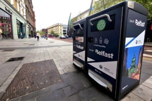 Two Bigbelly smart waste and recycling bins with Smart Belfast branding on a paved city sidewalk.