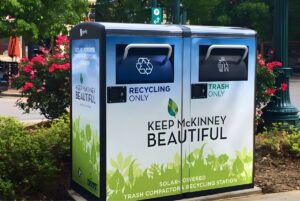 Solar-powered trash compactor and recycling station on a sidewalk in McKinney, Texas.