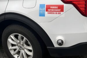 Close-up of a white vehicle with a parking enforcement camera and a Smart Streets pilot program decal.