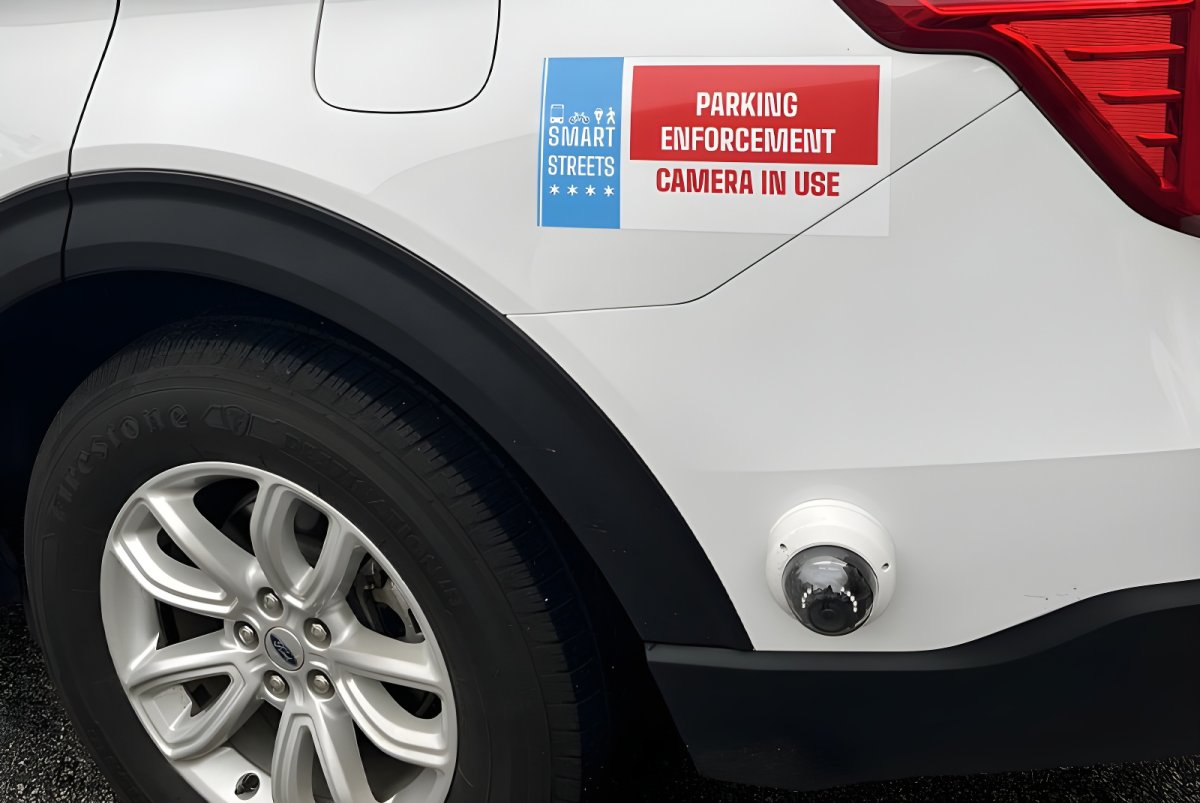 Close-up of a white vehicle with a parking enforcement camera and a Smart Streets pilot program decal.