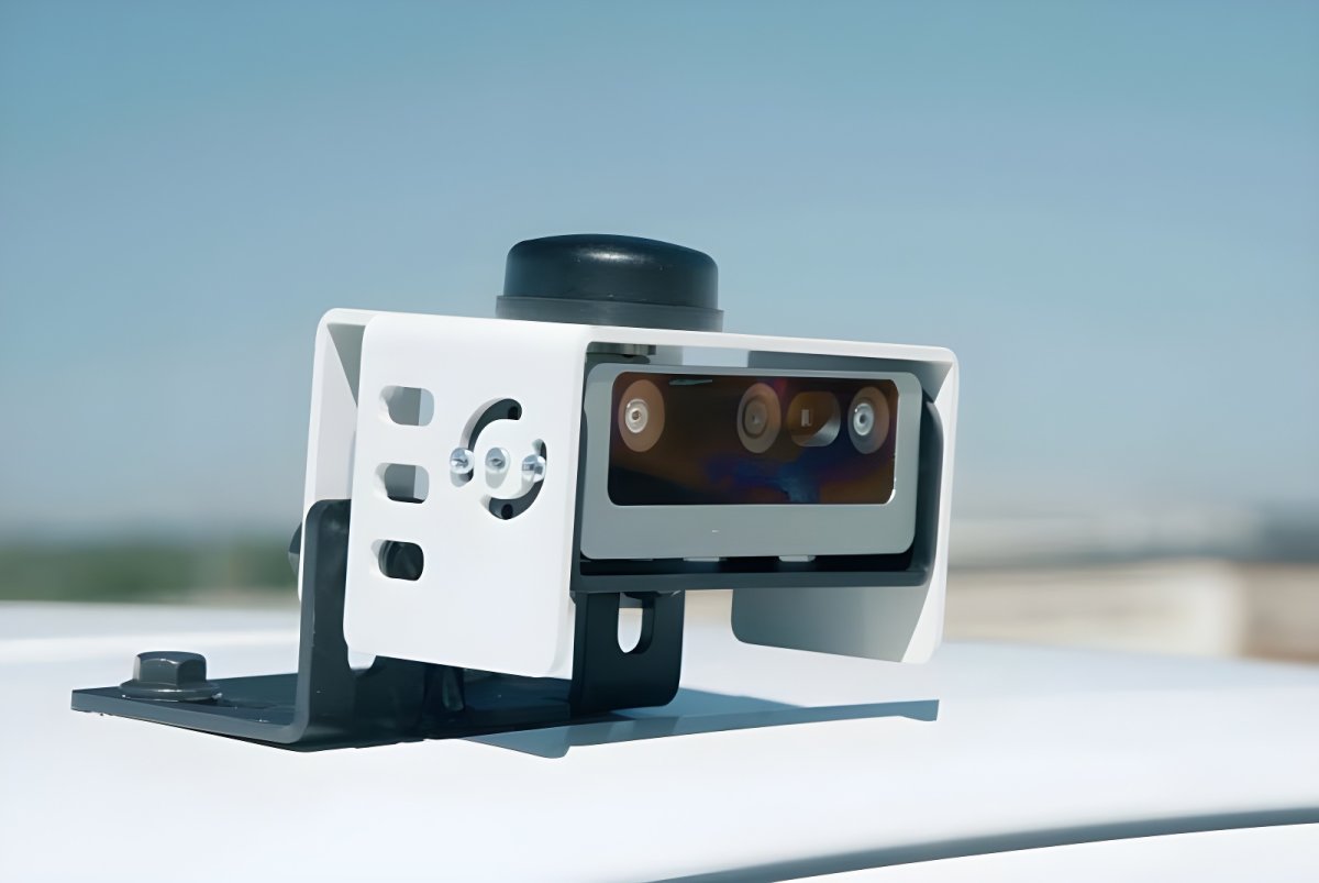 A City Detect AI-powered camera sensor mounted on a white vehicle roof against a clear blue sky.