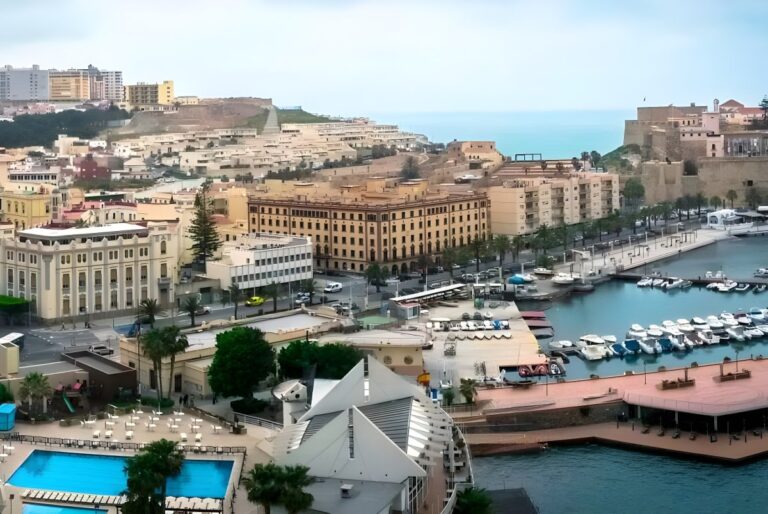 Elevated view of the Melilla harbor featuring docked boats, coastal architecture, and the historic city fortress.